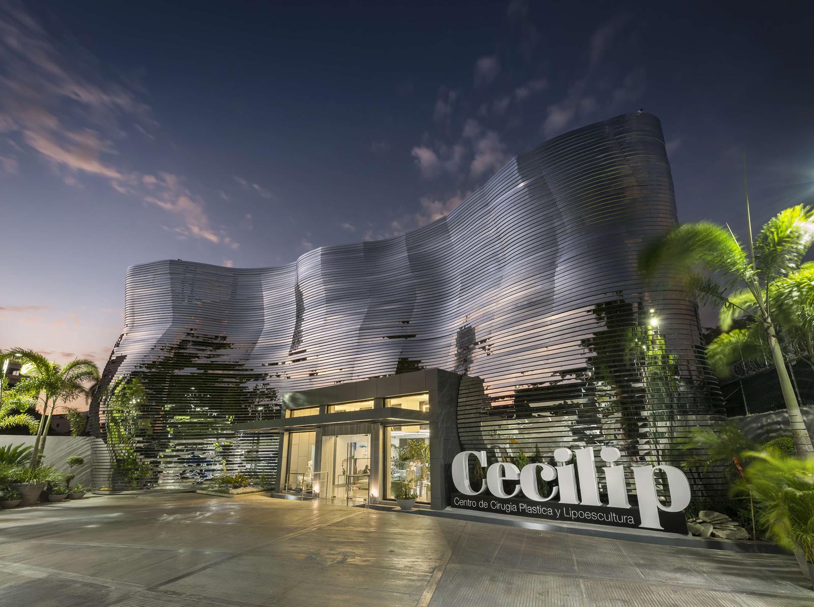 Fachada de CECILIP - Centro de Cirugía Plástica y Lipoescultura en Santo Domingo, con su distintiva fachada ondulada iluminada al atardecer